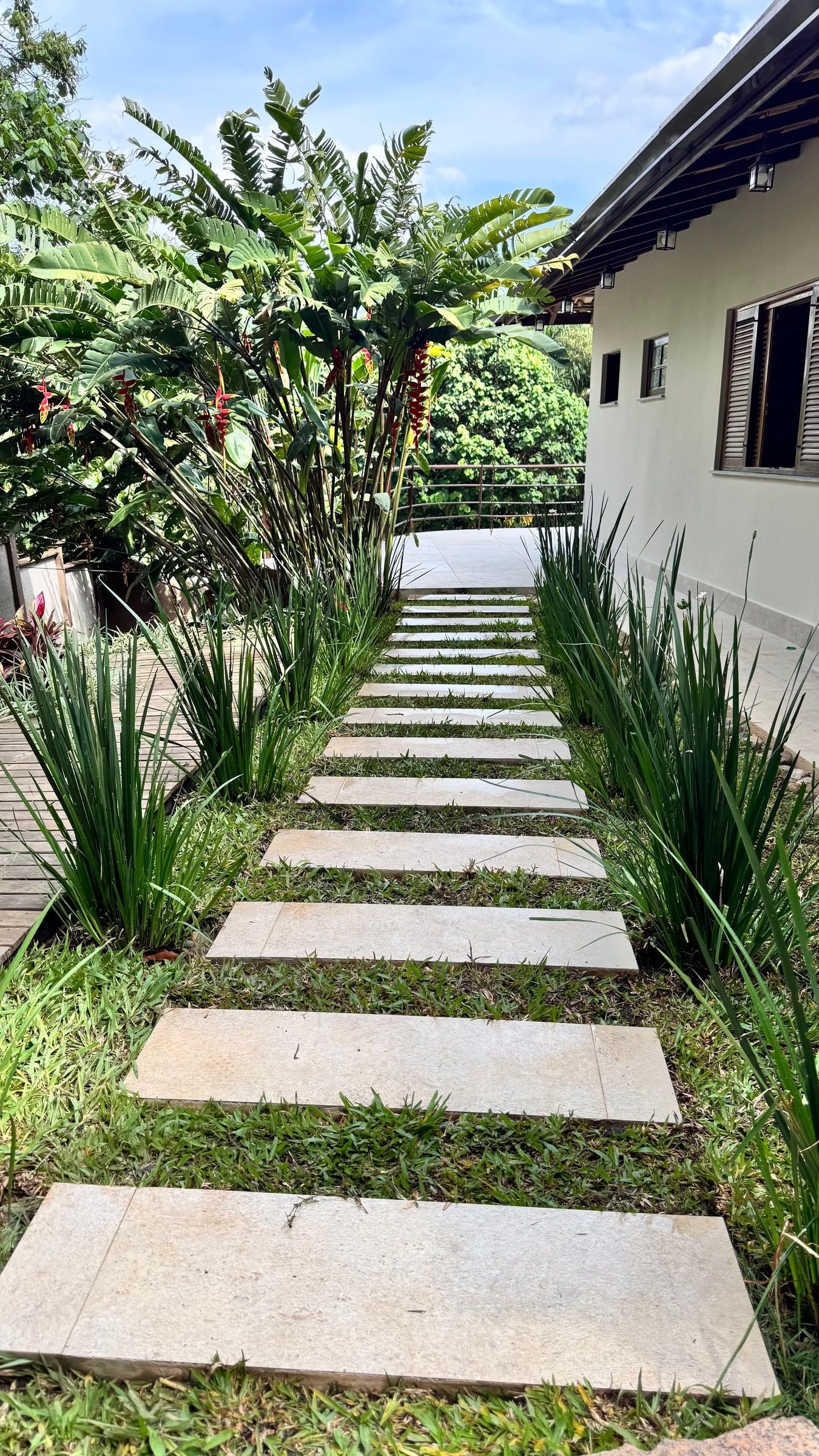 Caminho de placas de pedra entre grama e capim, jardim feito pela Alpha